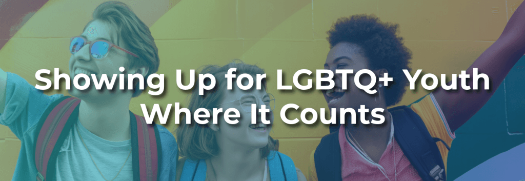 Three smiling LGBTQ+ youth standing together in front of a rainbow mural, representing community support, belonging, acceptance, and affirming spaces for young people.